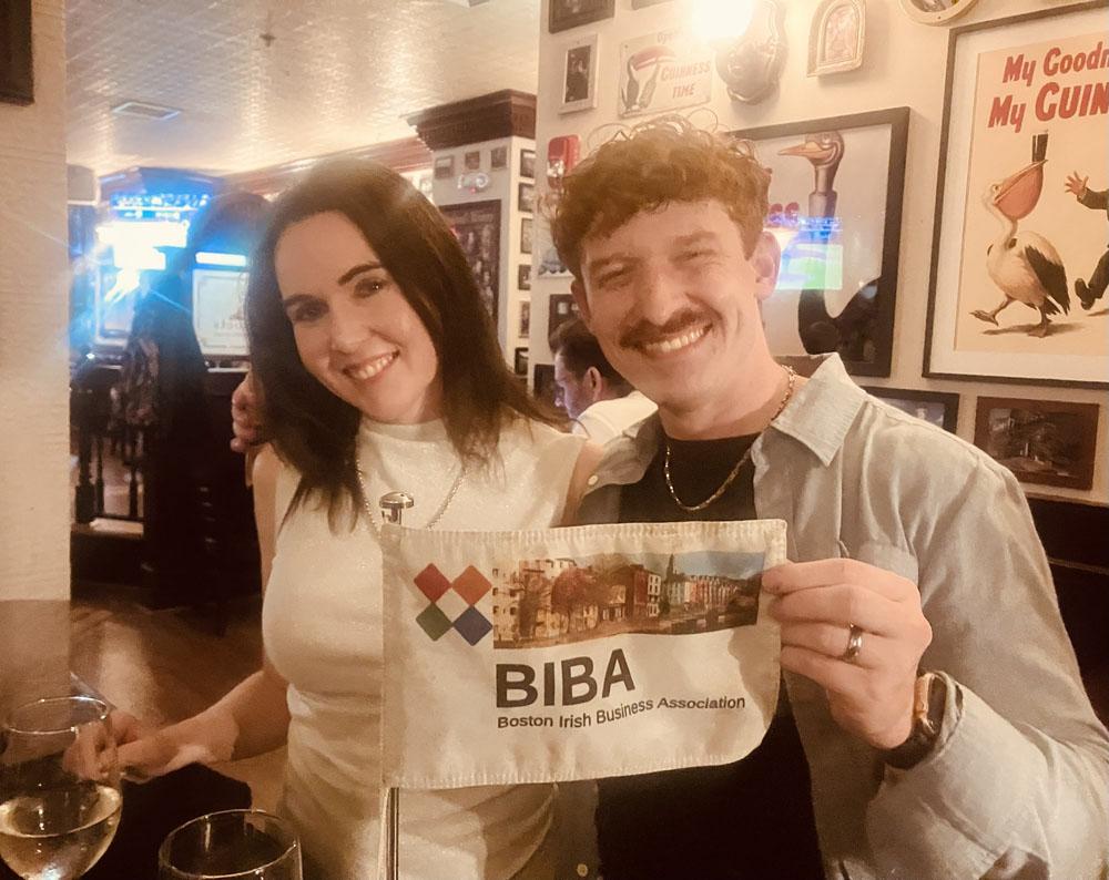 Two attendees smiling and holding a small BIBA flag in an Irish pub